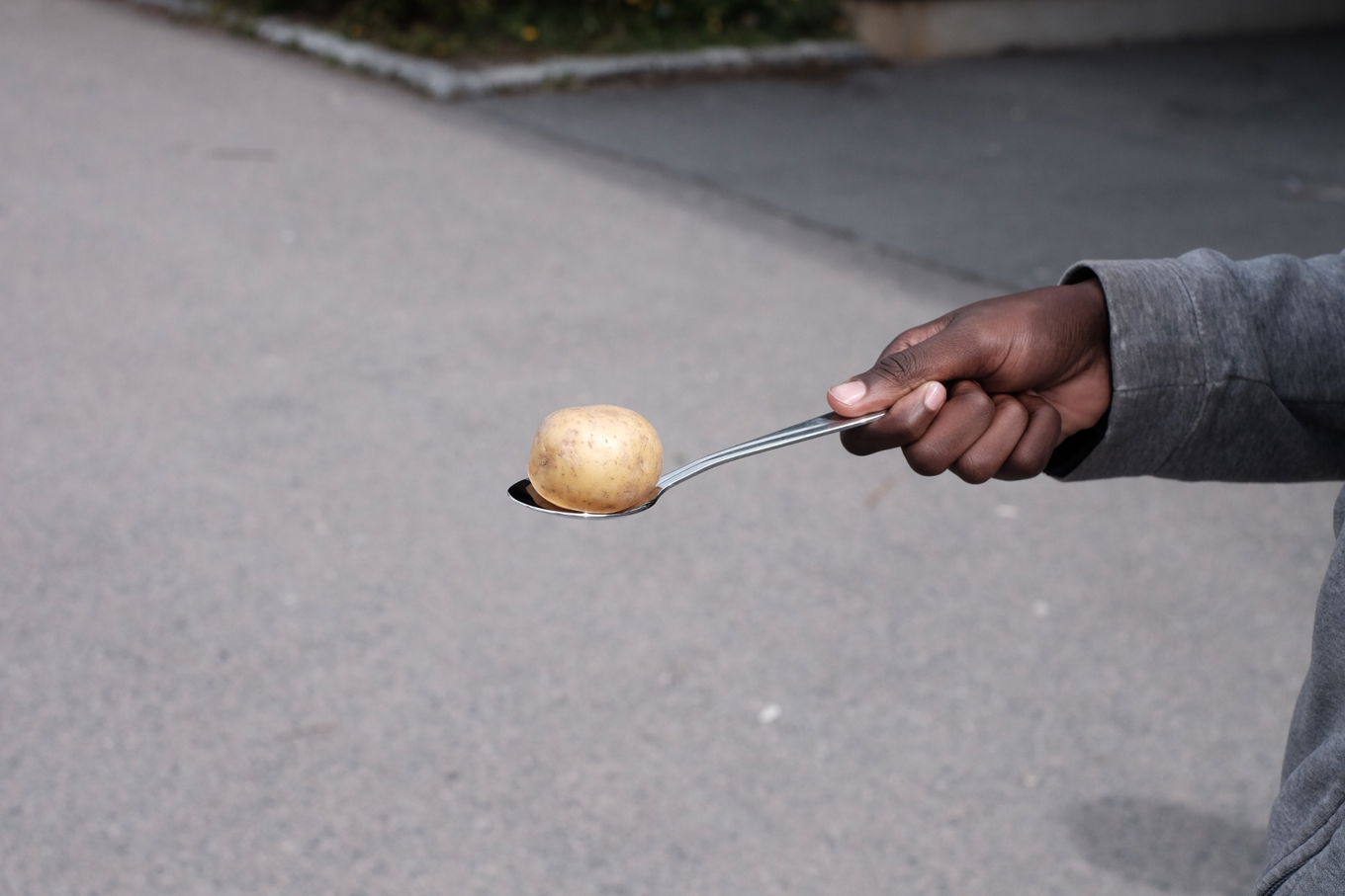 en hånd som holder en skje over et hvitt egg på en grå overflate