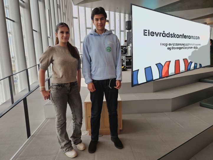 en person og en person som står foran et skilt en person og en person som står foran et skilt