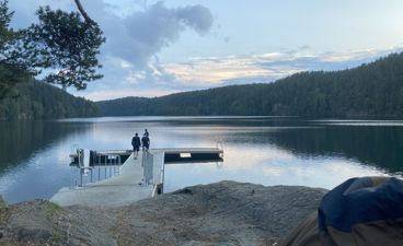 en gruppe mennesker på en brygge over en innsjø