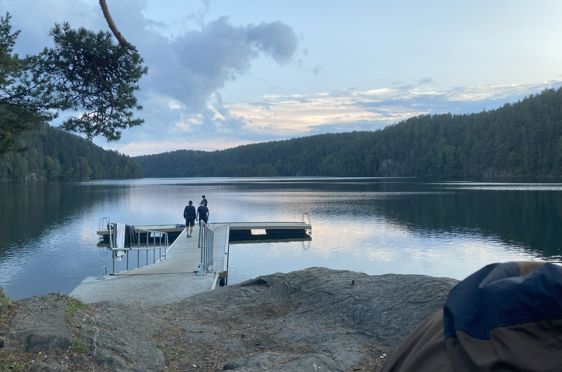 en gruppe mennesker på en brygge over en innsjø
