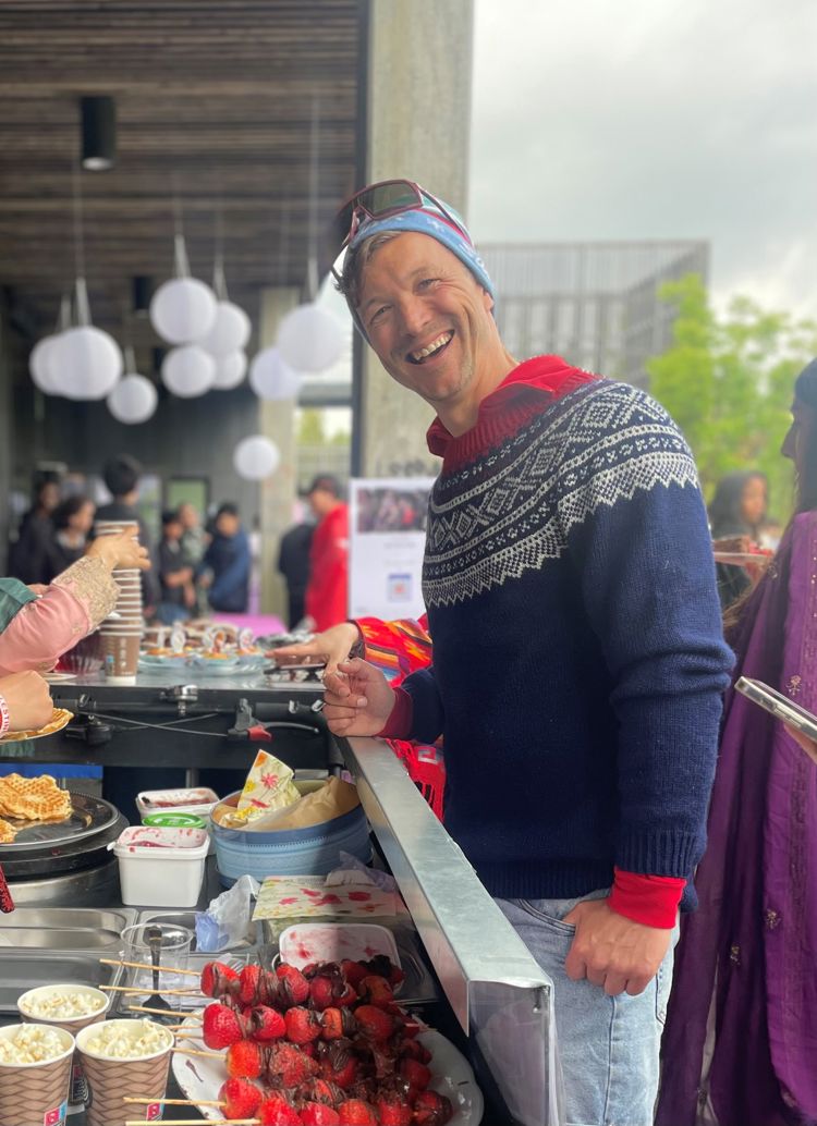 en person som smiler og står ved siden av et bord fullt av mat