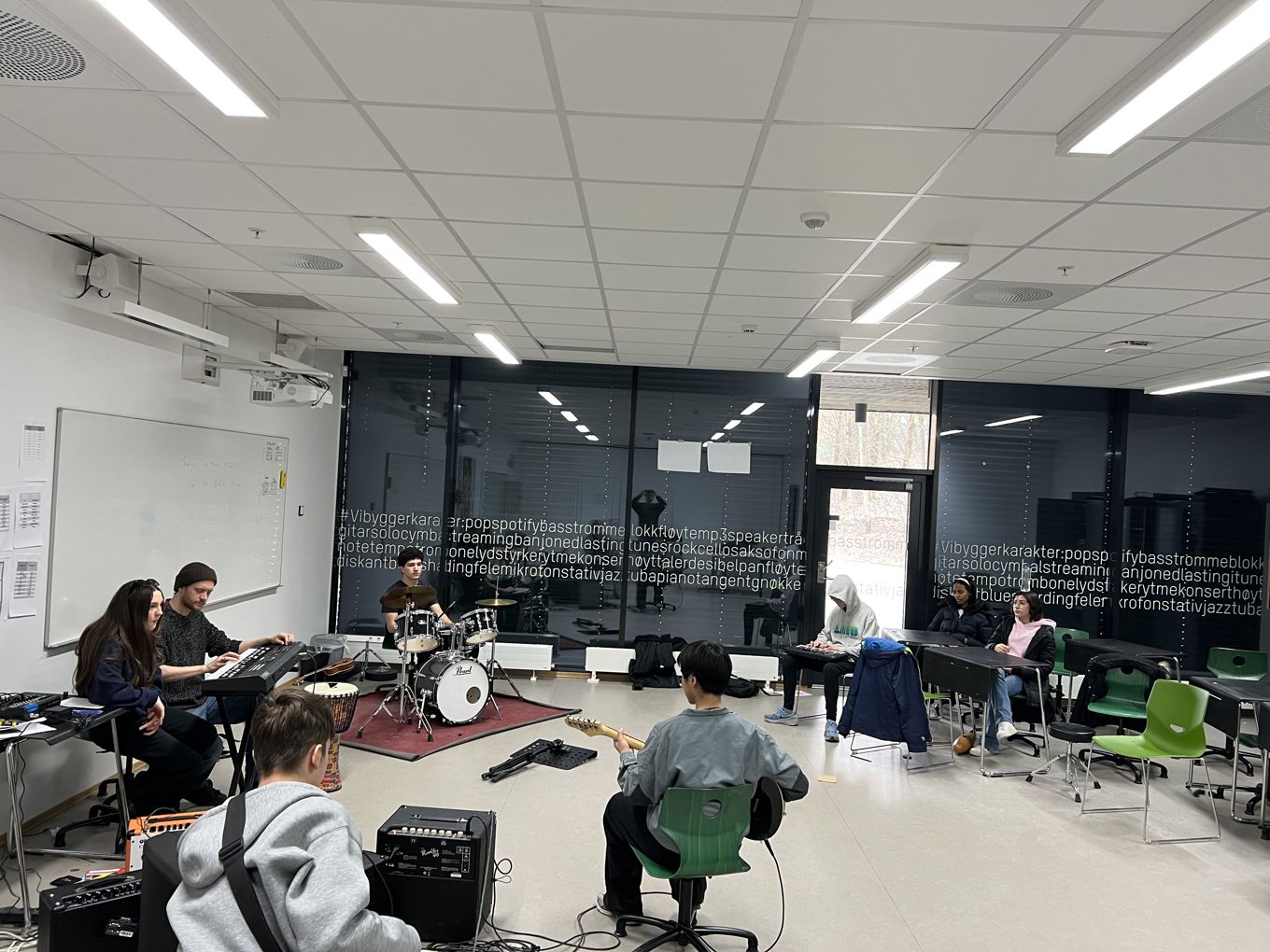 en gruppe mennesker som sitter ved bord i et rom med en tavle